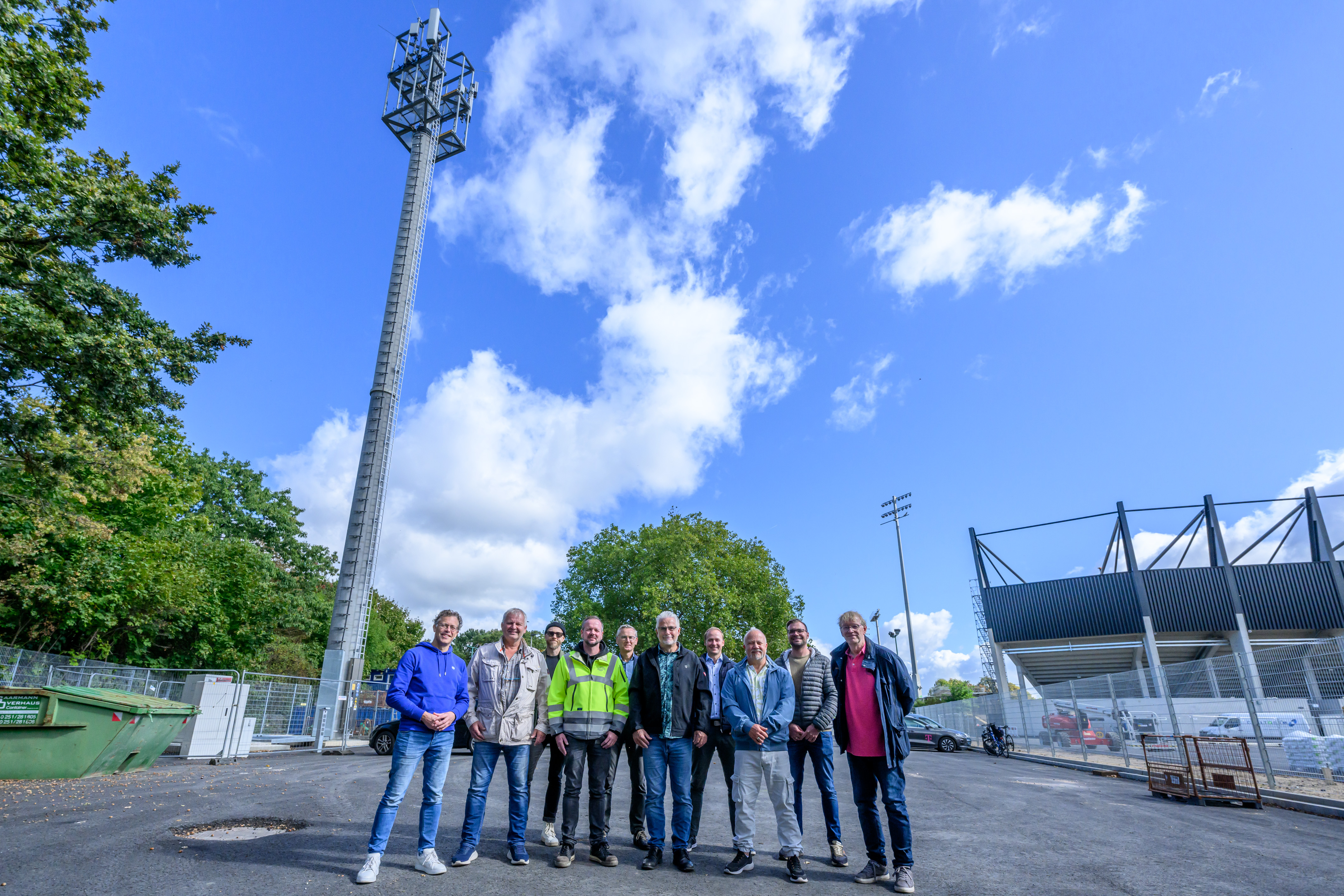 Eine Gruppe aus zehn Männern vor der Kulisse aus Funkmast und Stadion
